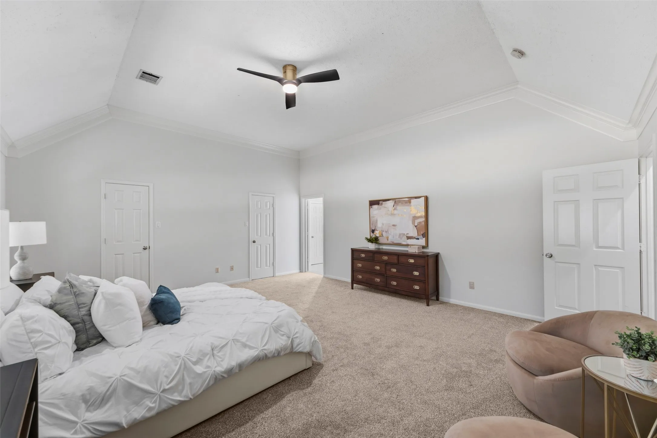 Vaulted ceiling with crown molding, ceiling fan, and carpet flooring