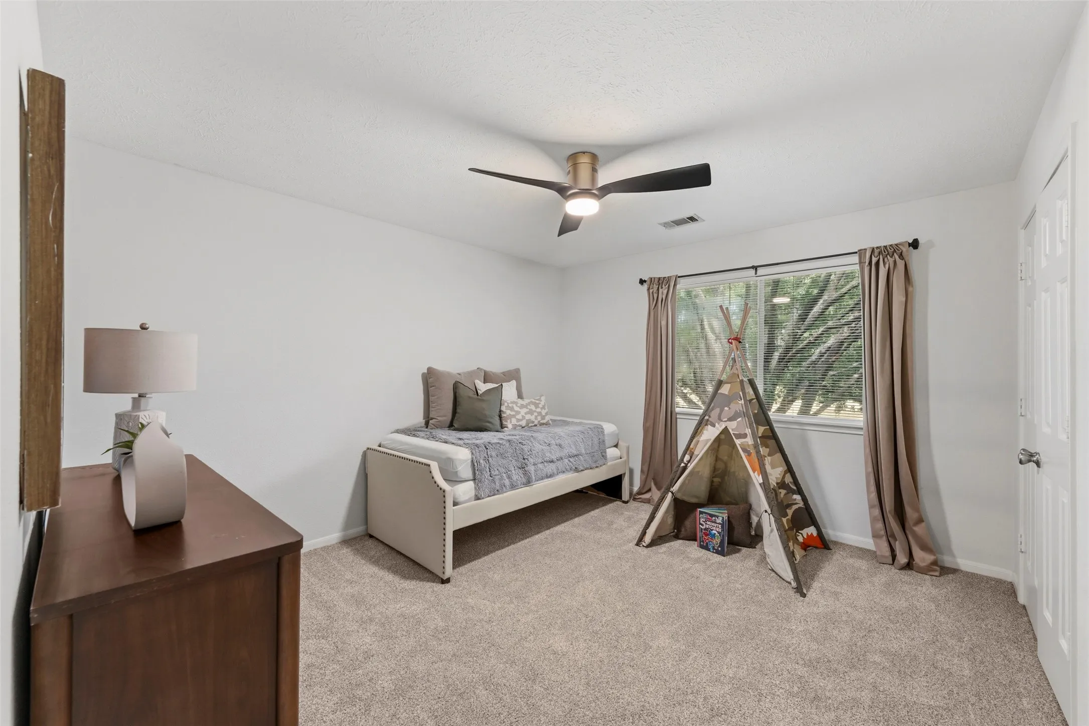 Bright room with wall-to-wall carpeting, white walls, and a ceiling fan