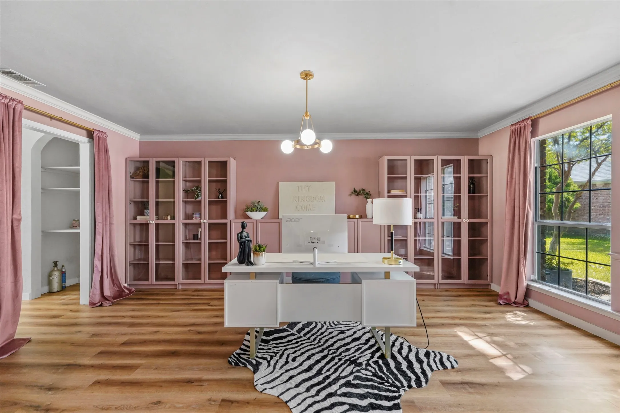 Recessed shelving, built-in display cabinetry, wood-finish flooring, crown molding, and a large window