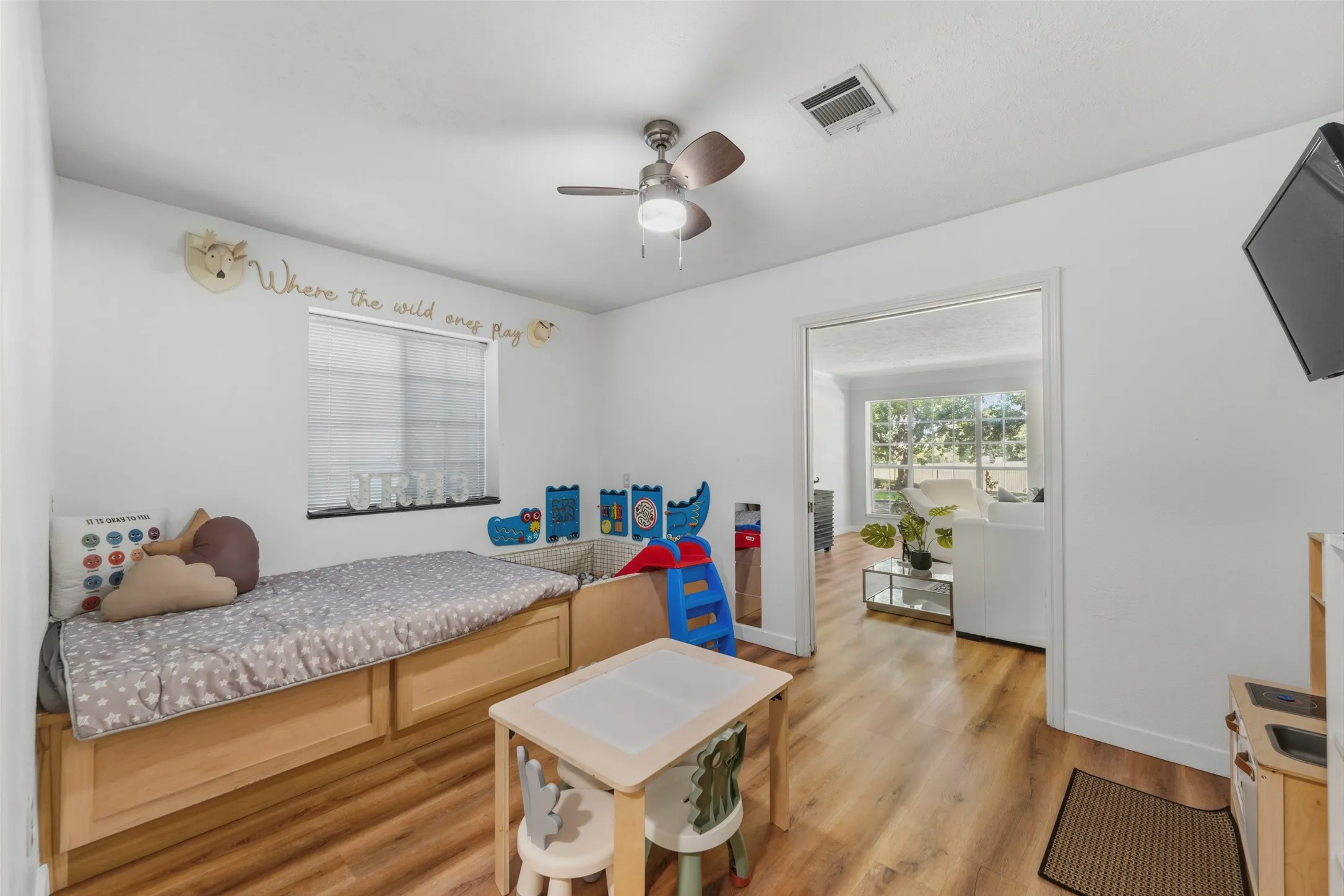 Wood-finish flooring, ceiling fan with integrated lighting, window with blinds, and white painted walls
