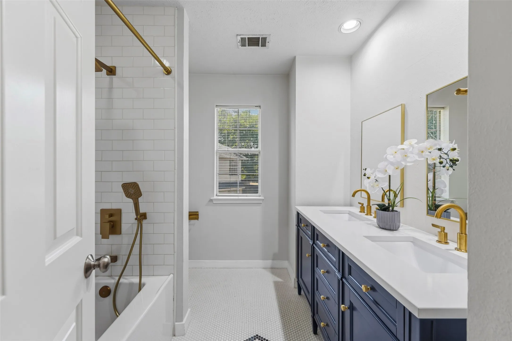 Bathroom featuring a dual-sink vanity with a blue cabinet, white countertop, and gold-finish fixtures