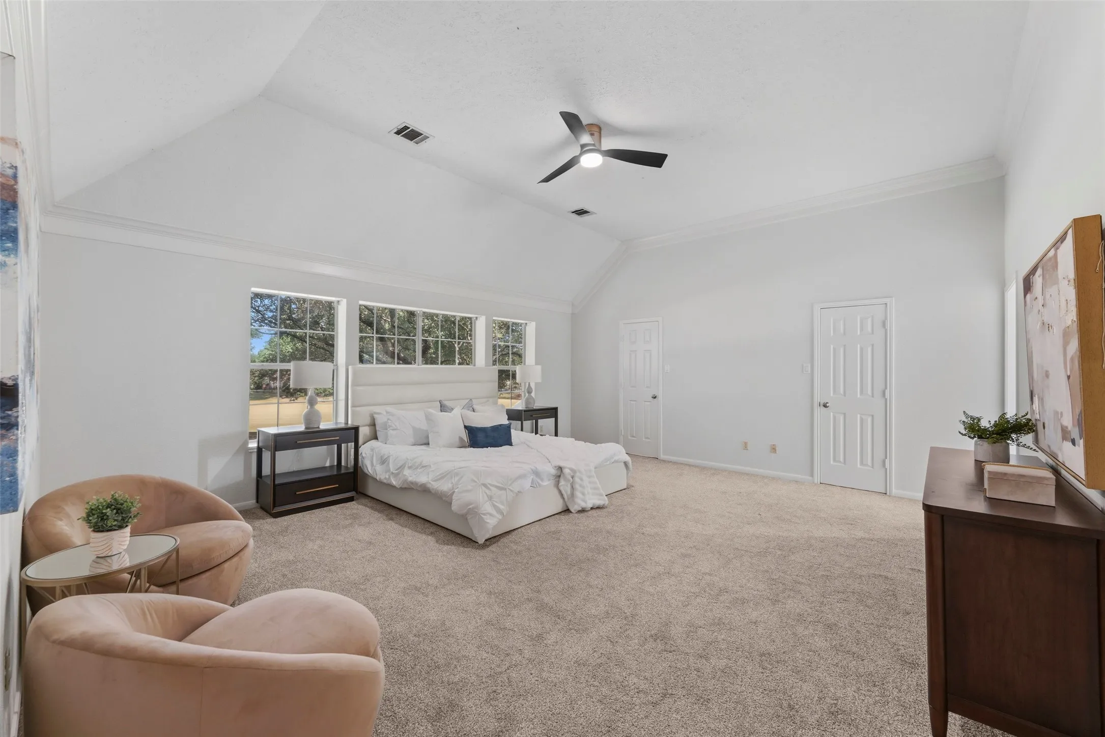 Spacious room featuring a vaulted ceiling with crown molding, a ceiling fan, and multiple windows