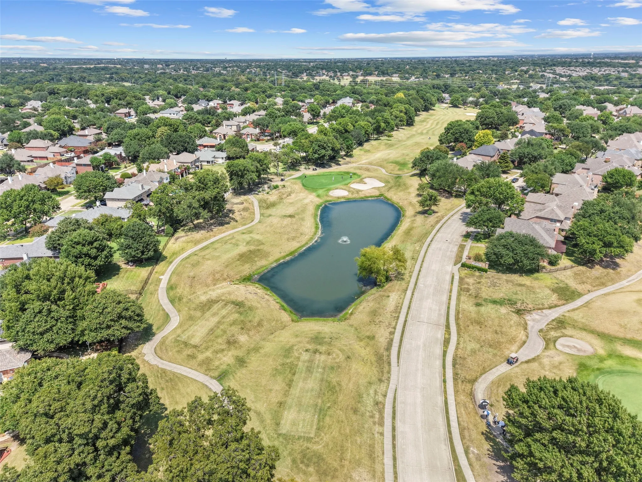 Lush green spaces, golf course proximity, private pond, and winding pathways define this community setting