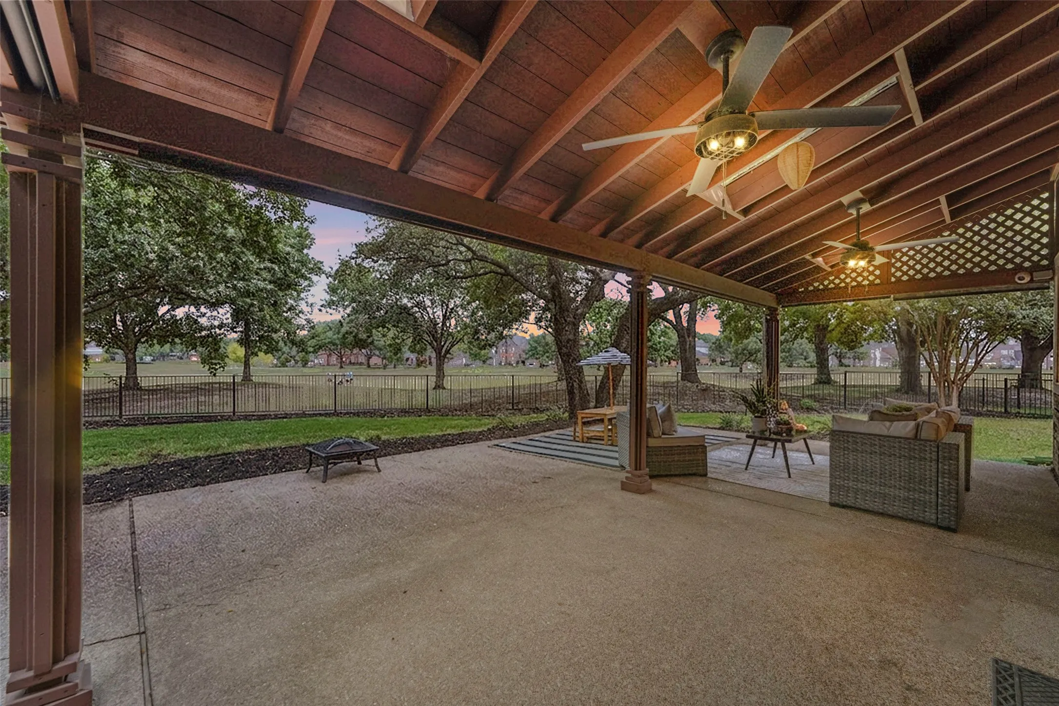 Expansive concrete patio with a wood-finish vaulted ceiling, supported by decorative columns