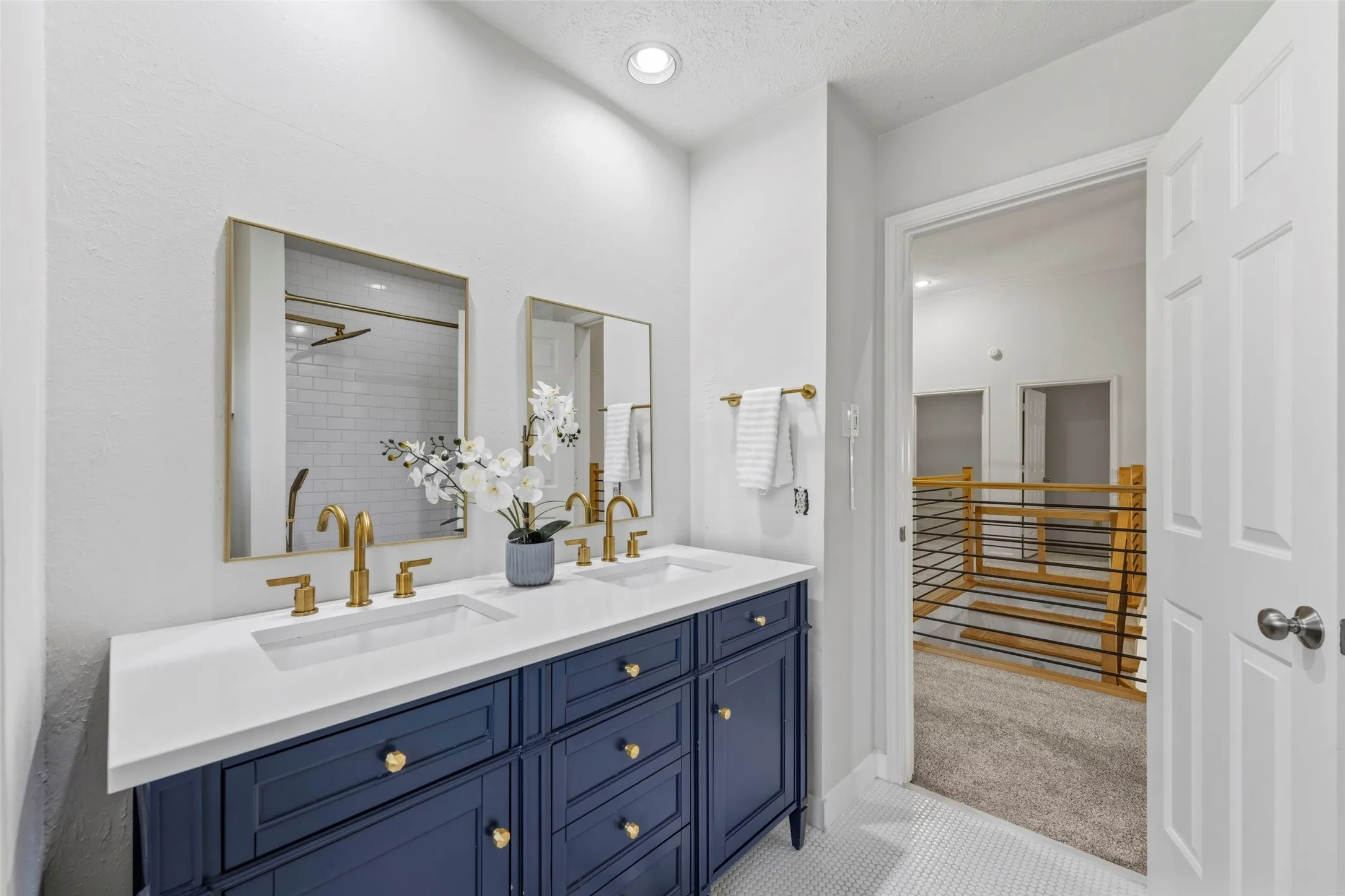 Dual vanity with a white countertop and navy cabinetry, gold-finish fixtures, and individual framed mirrors