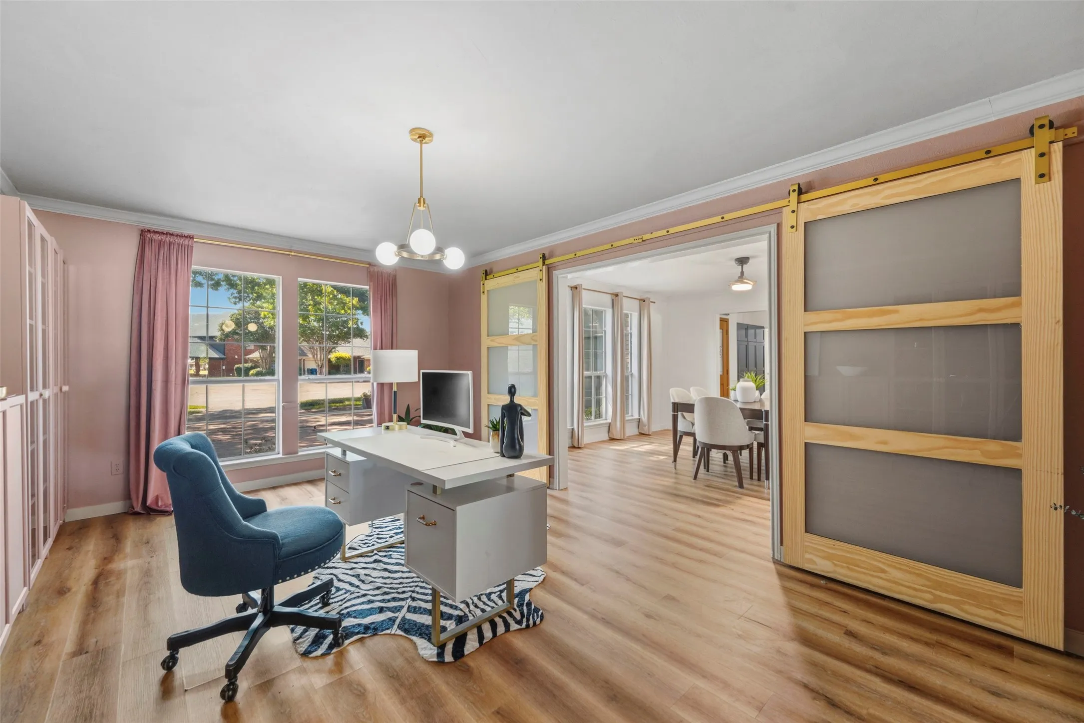 Wood-finish flooring, built-in shelving, large window, and a modern chandelier