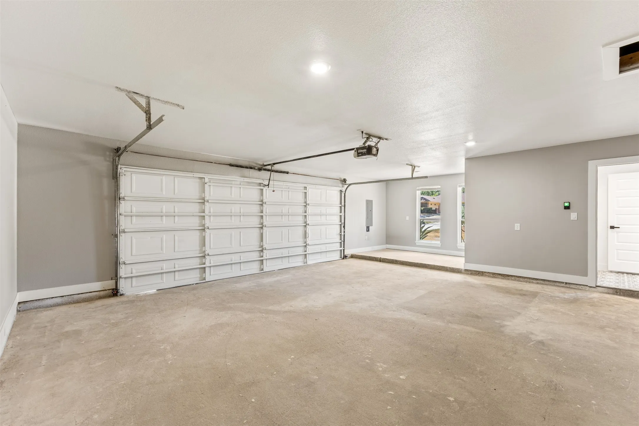 Two-car garage featuring a concrete floor, light gray walls, and recessed lighting
