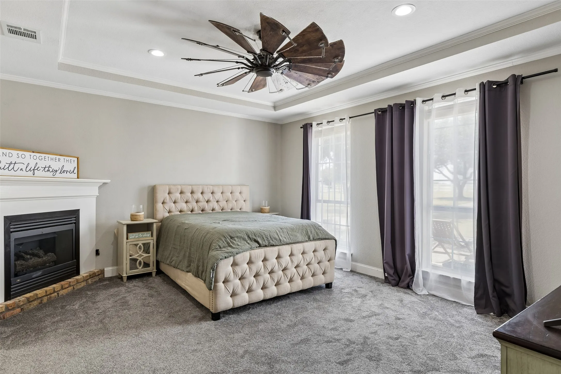 Tray ceiling, recessed lighting, ceiling fan, fireplace with mantel, and multiple windows