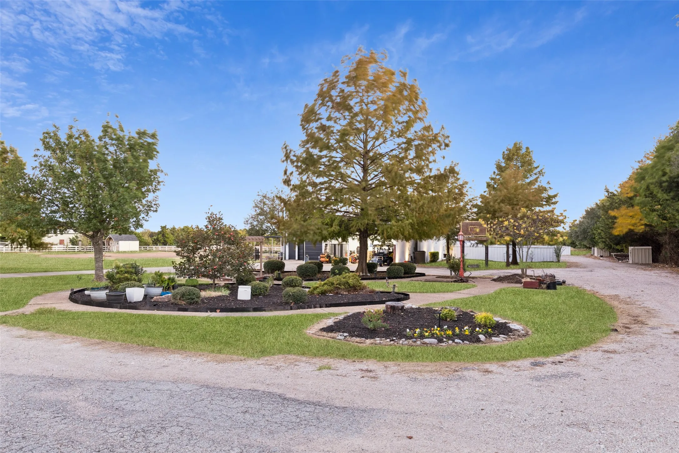 Expansive outdoor area featuring mature trees, landscaped garden beds, and gravel pathways