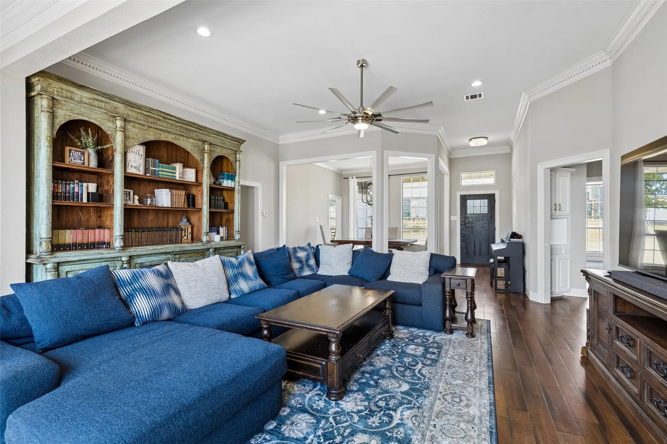 Hardwood flooring, crown molding, built-in shelving, ceiling fan, and recessed lighting