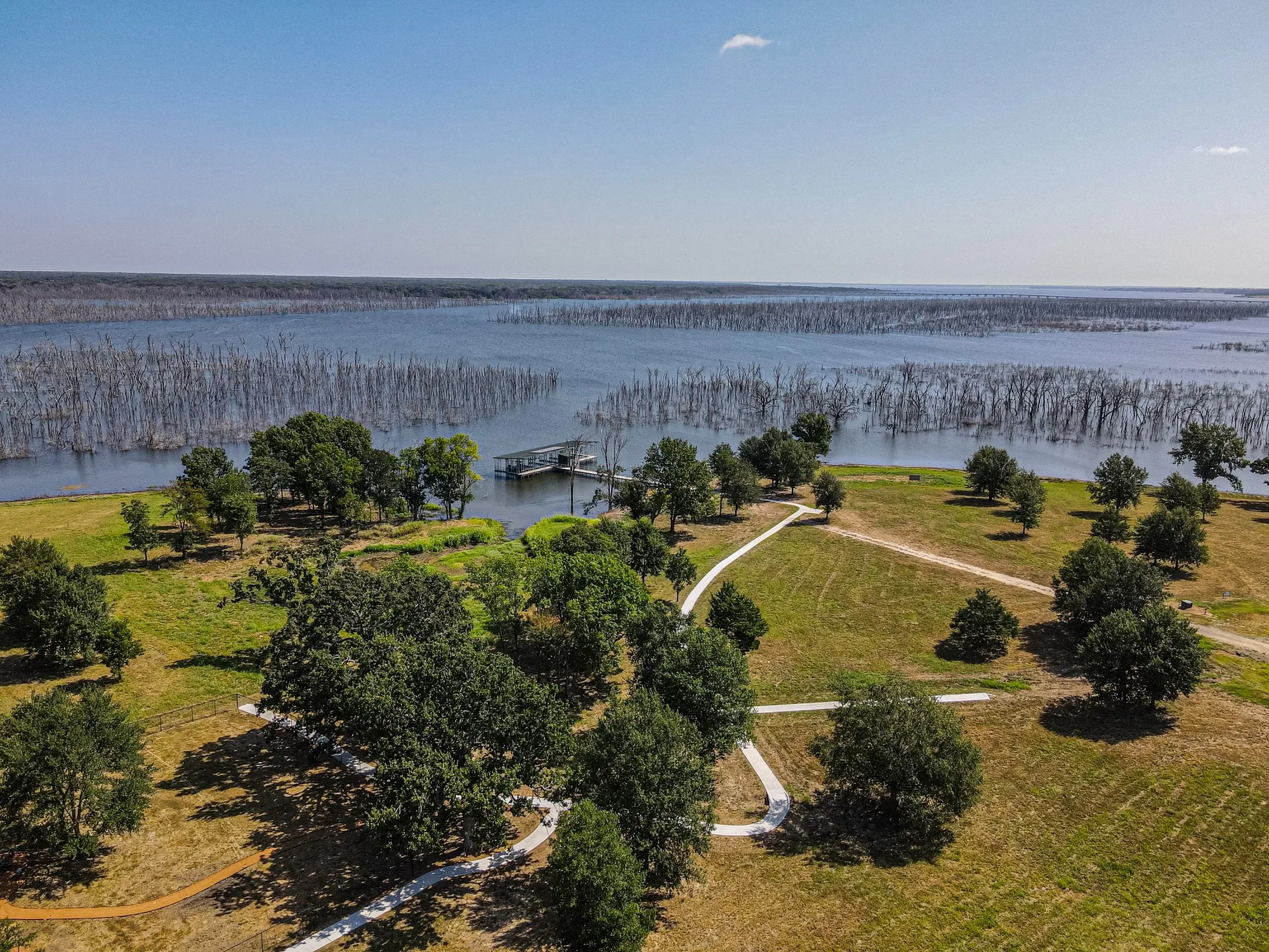 Expansive waterfront property with direct lake access, featuring a private boat dock, winding pathways, and mature trees