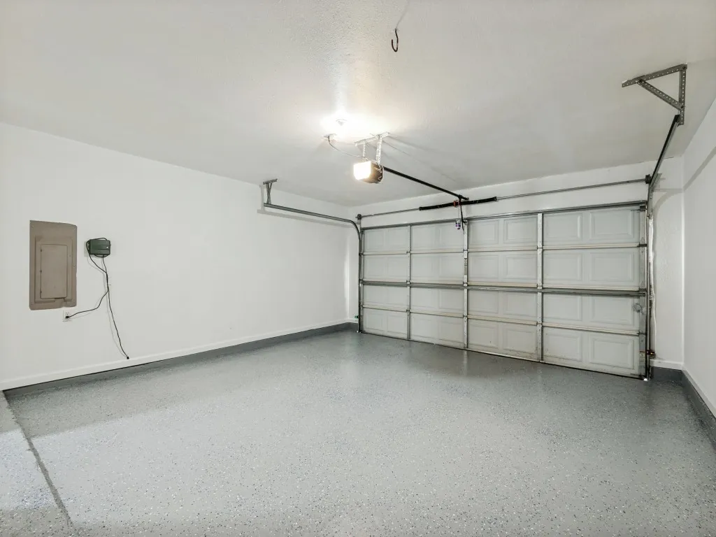 Spacious garage featuring a paneled overhead door, overhead lighting, and an epoxy-coated floor