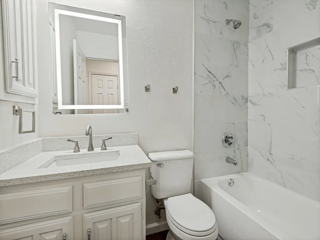 Spa-inspired bathroom featuring a marble-look tile shower enclosure with integrated shelving, white subway tile accents, and polished chrome fixtures