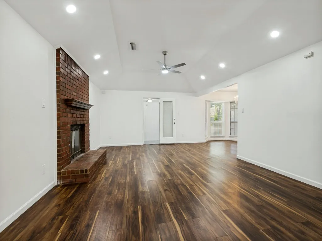 Vaulted ceiling, brick fireplace with mantel, wood-finish flooring, recessed lighting, and ceiling fan