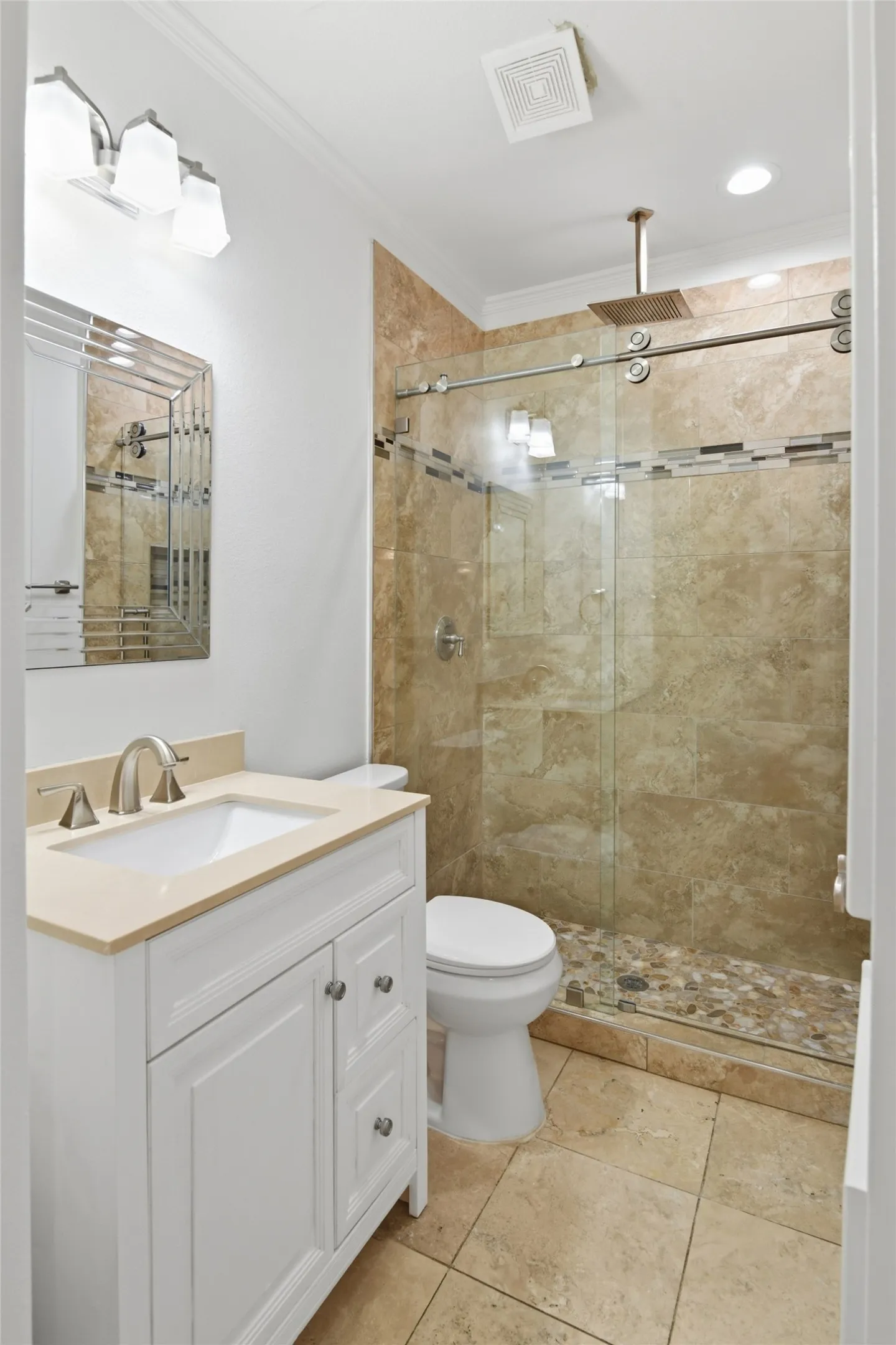 Walk-in shower with natural stone tile and a pebble floor