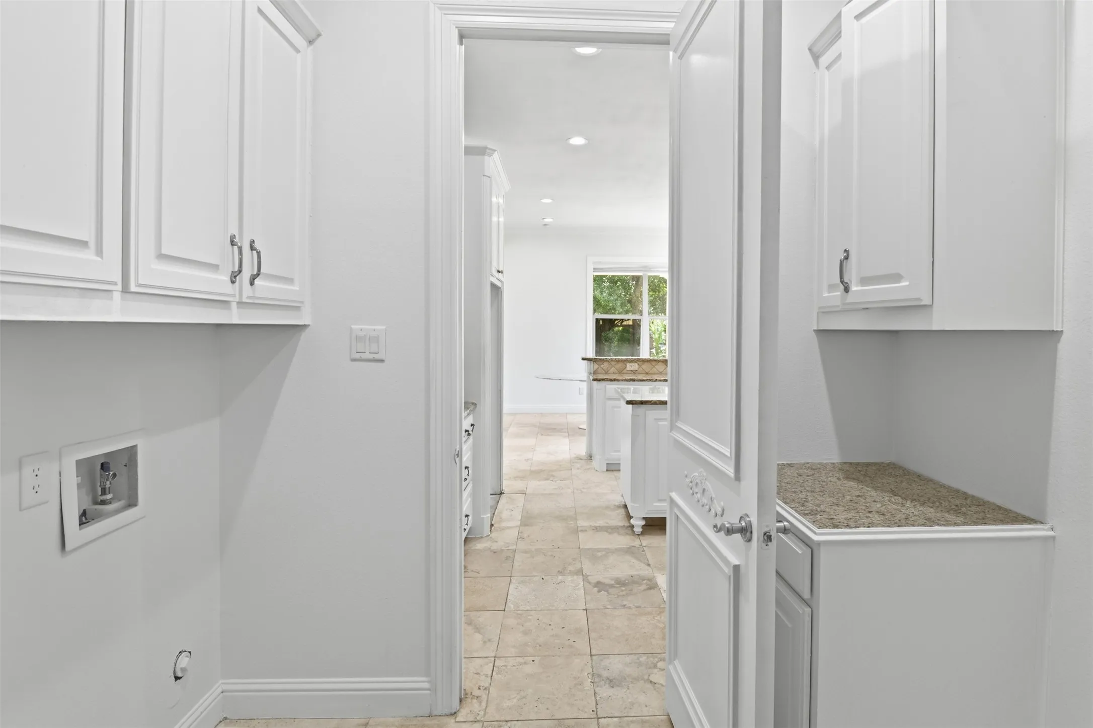 White cabinetry with brushed nickel hardware, granite-style countertops, and tiled flooring
