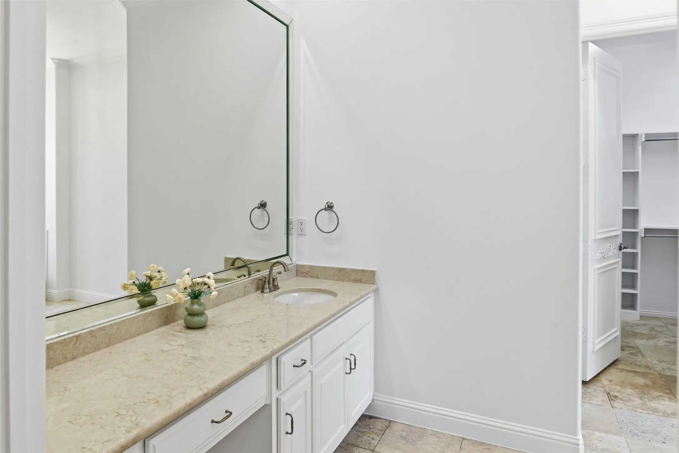 Vanity with stone countertop, undermount sink, and white cabinetry