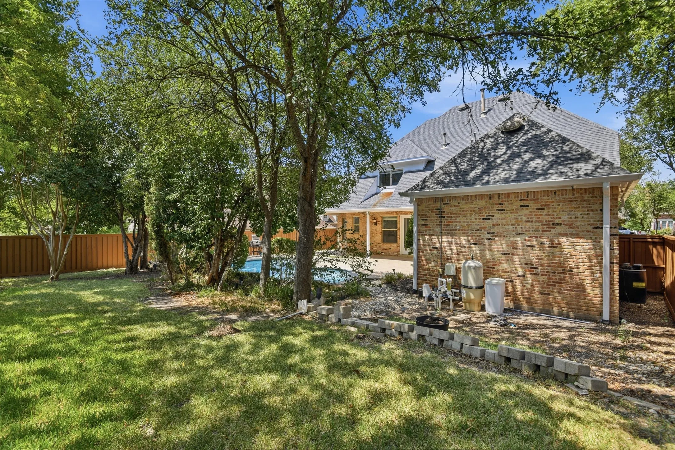 Expansive backyard with a manicured lawn, established trees, and a swimming pool