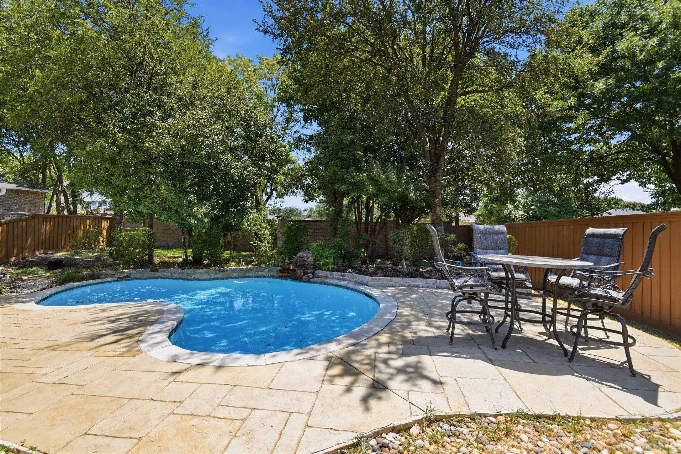 Kidney-shaped swimming pool with stone coping, surrounded by a flagstone patio
