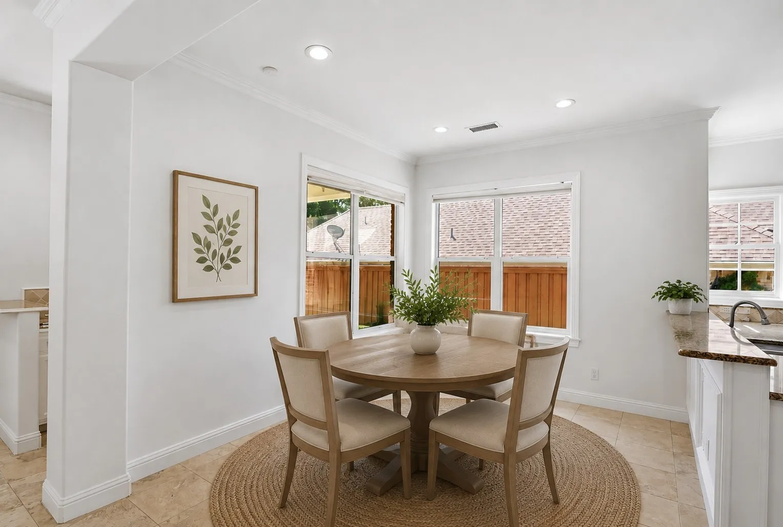 Recessed lighting illuminates the dining area, featuring multiple windows with white trim and crown molding