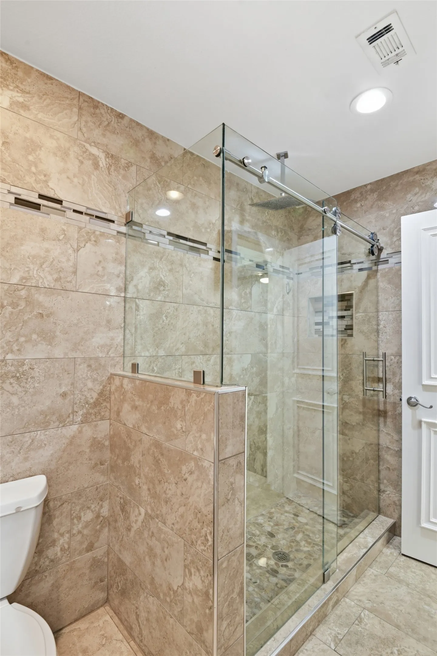 Walk-in shower with clear glass enclosure and sliding door