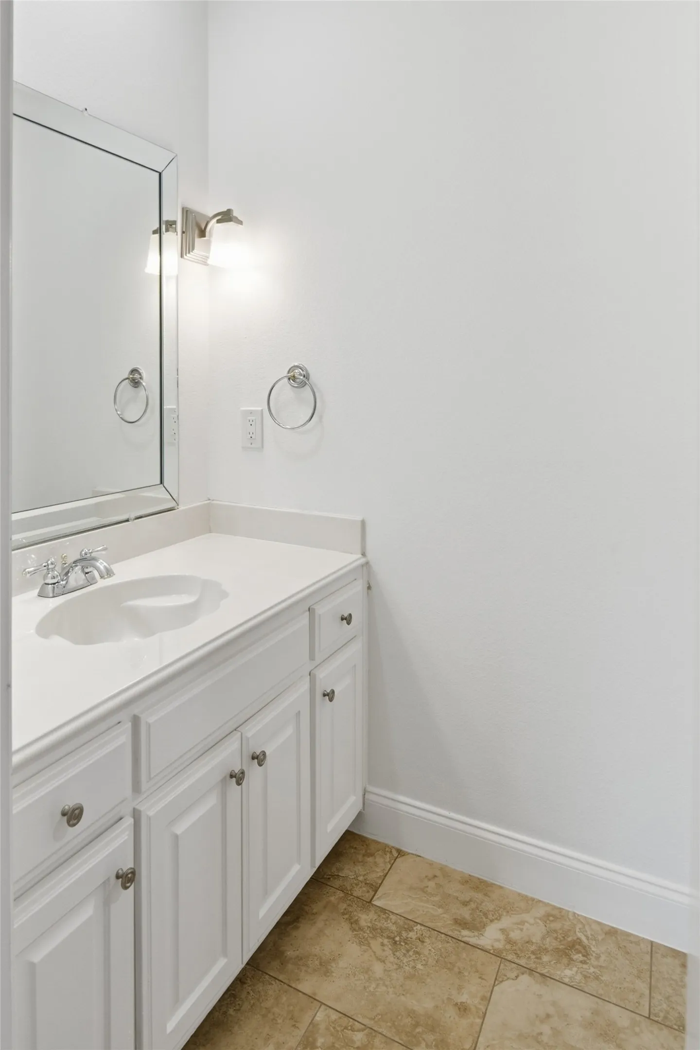 White vanity with recessed panel cabinet doors, brushed nickel hardware, integrated sink, and coordinating countertop