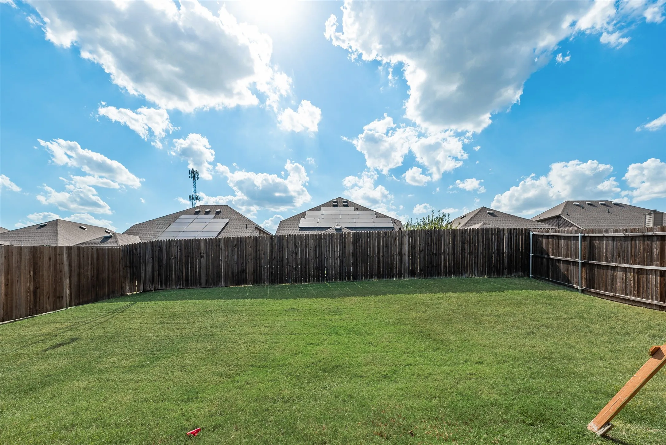 Expansive backyard featuring a manicured lawn and a privacy fence