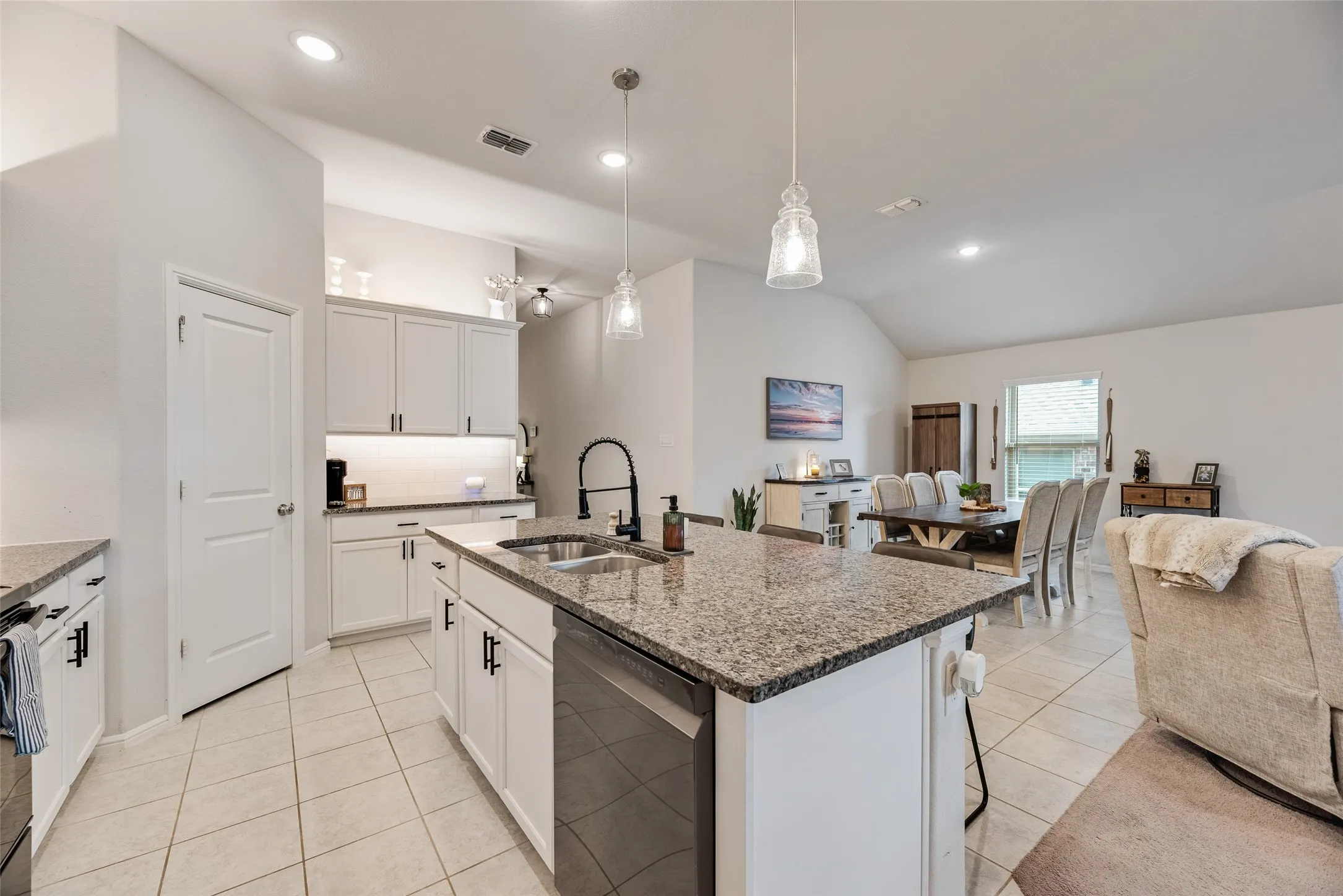 Kitchen featuring a center island with granite countertop, integrated sink, and dishwasher