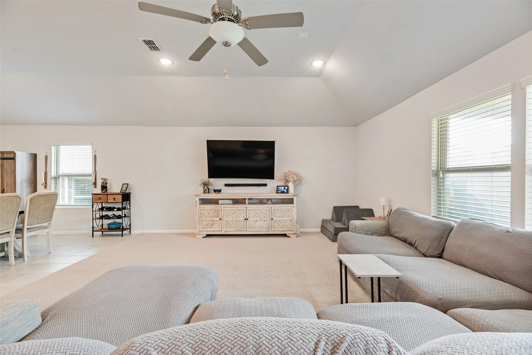 Vaulted ceiling with recessed lighting and a ceiling fan, carpeted flooring, and large windows with blinds