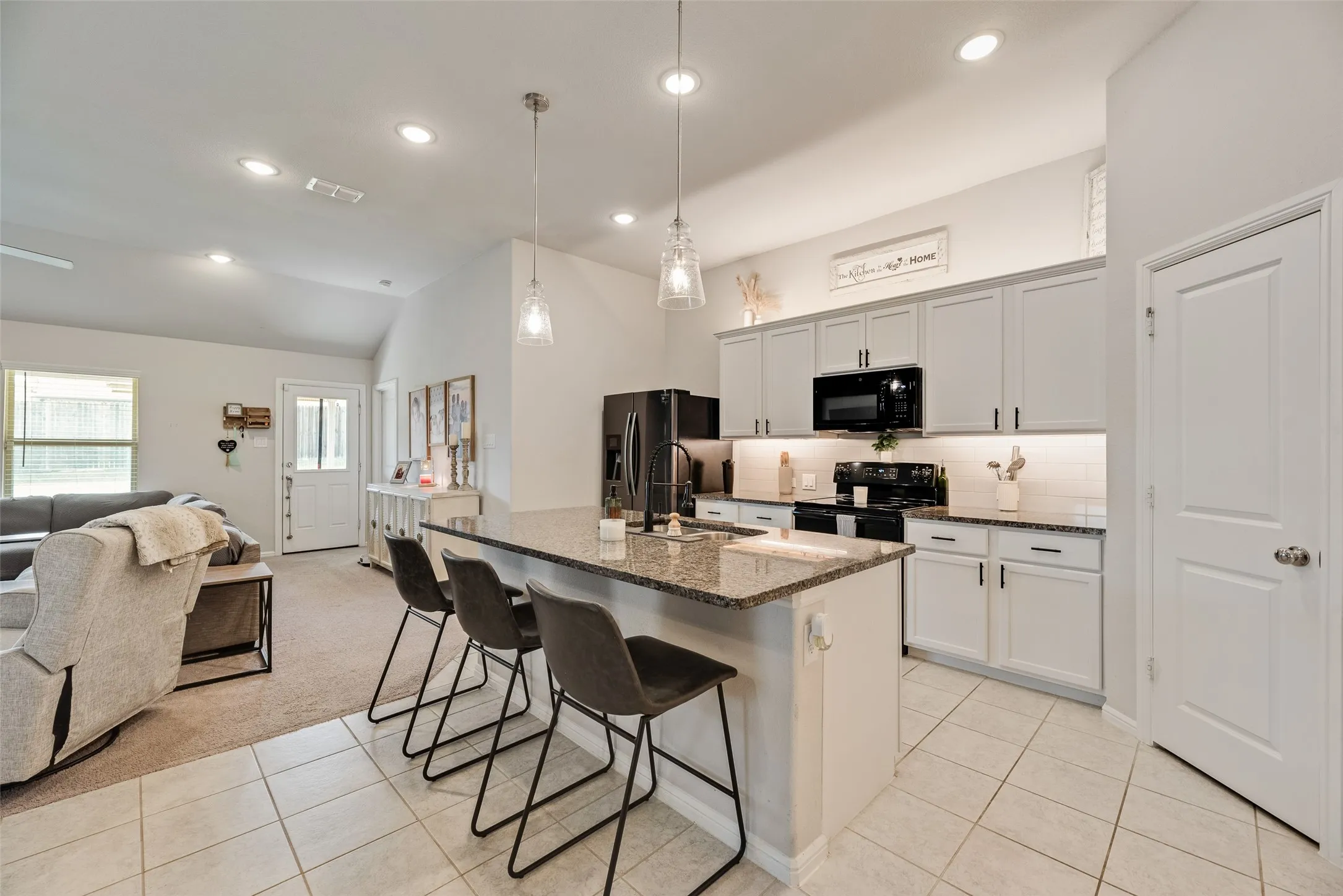 Kitchen featuring an island with granite countertops, light-toned cabinetry, and recessed lighting