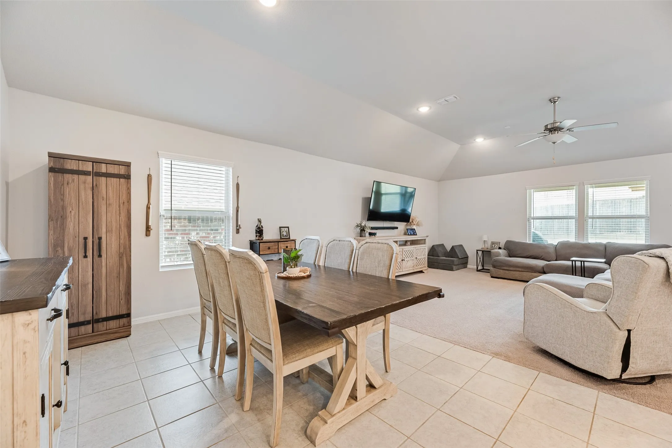 Vaulted ceilings with recessed lighting, integrated ceiling fan, tiled flooring, carpeting, and multiple windows with blinds