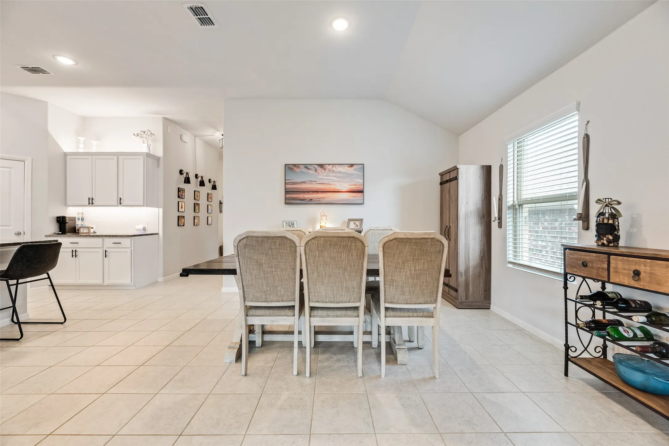 Vaulted ceiling, recessed lighting, tile flooring, white cabinetry, and a window with blinds