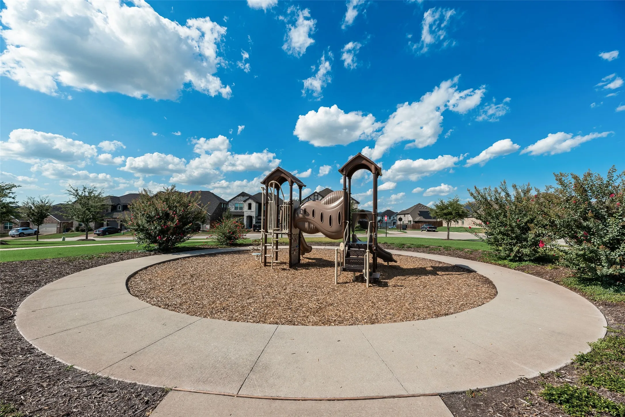 Community playground with integrated slides and climbing features, surrounded by a circular concrete path