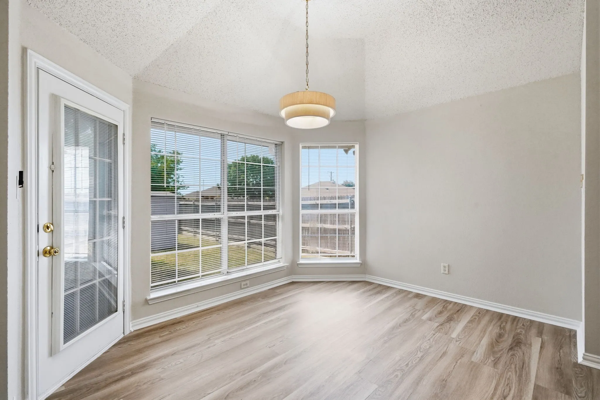 Dining area with vaulted ceiling, updated lighting & flooring, large windows with blinds & access to the outdoor space
