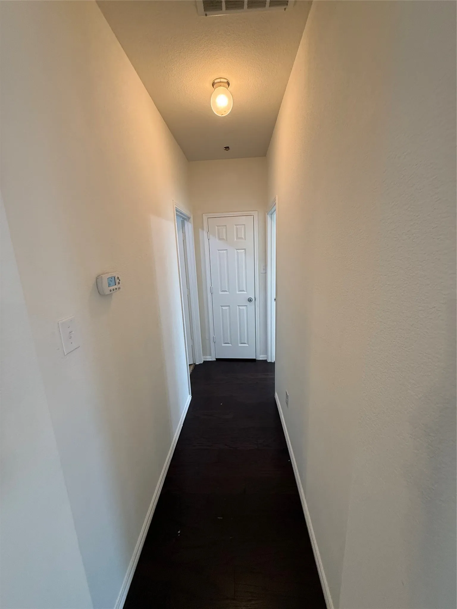 White interior doors, dark wood-finish flooring, and light wall paint