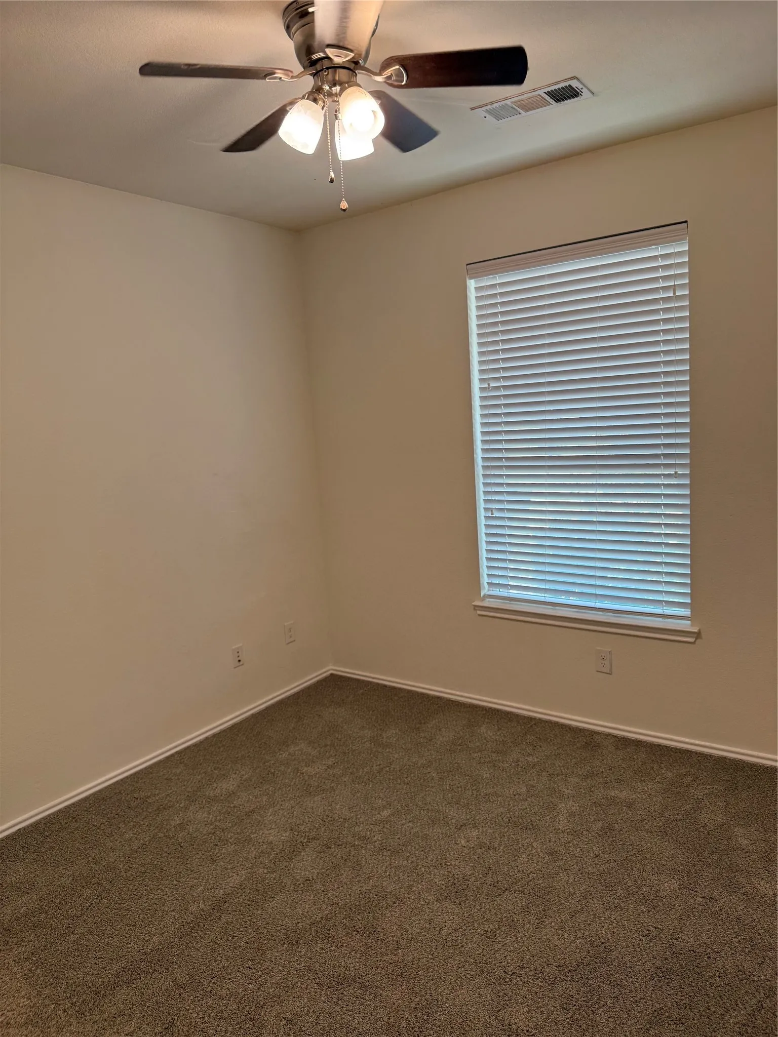 Neutral wall paint, carpeted flooring, window with blinds, and a ceiling fan with integrated lighting
