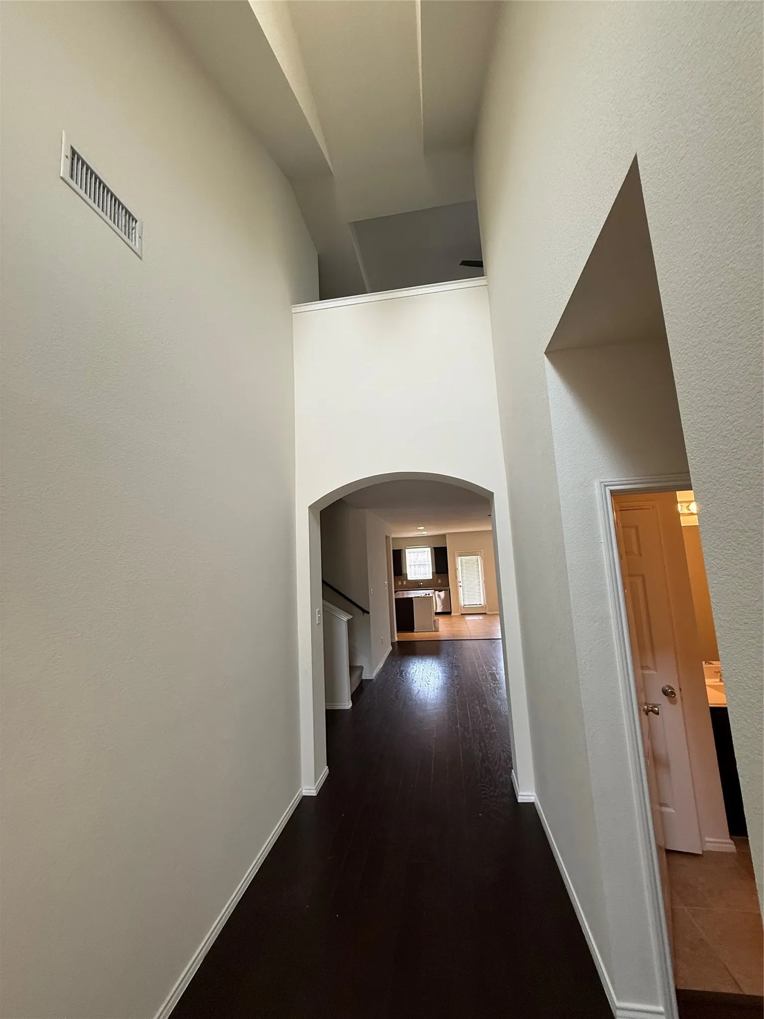 Entryway featuring high ceilings, dark wood-finish flooring, an arched doorway, and white trim