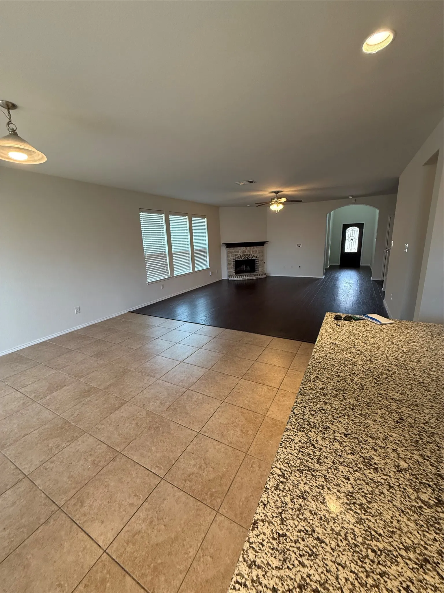 Expansive living area with tile flooring, a fireplace featuring a stone surround, and multiple windows