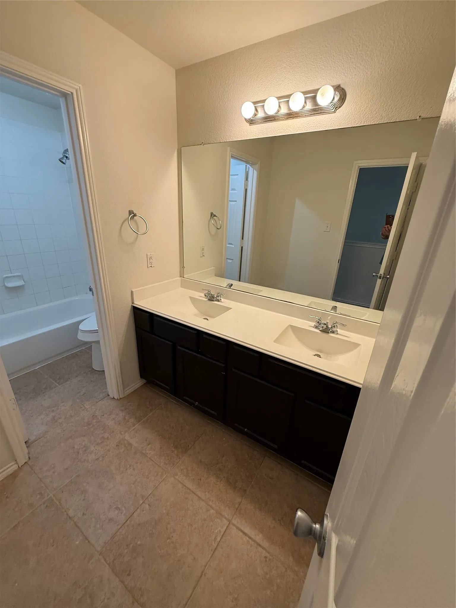 Dual vanity with integrated sinks, dark wood-finish cabinetry, and a full-width mirror