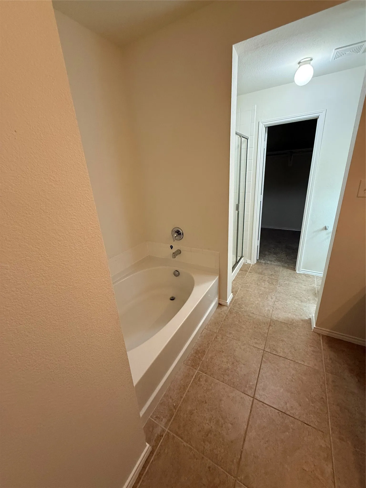 Built-in soaking tub with chrome fixtures, complemented by a tiled floor