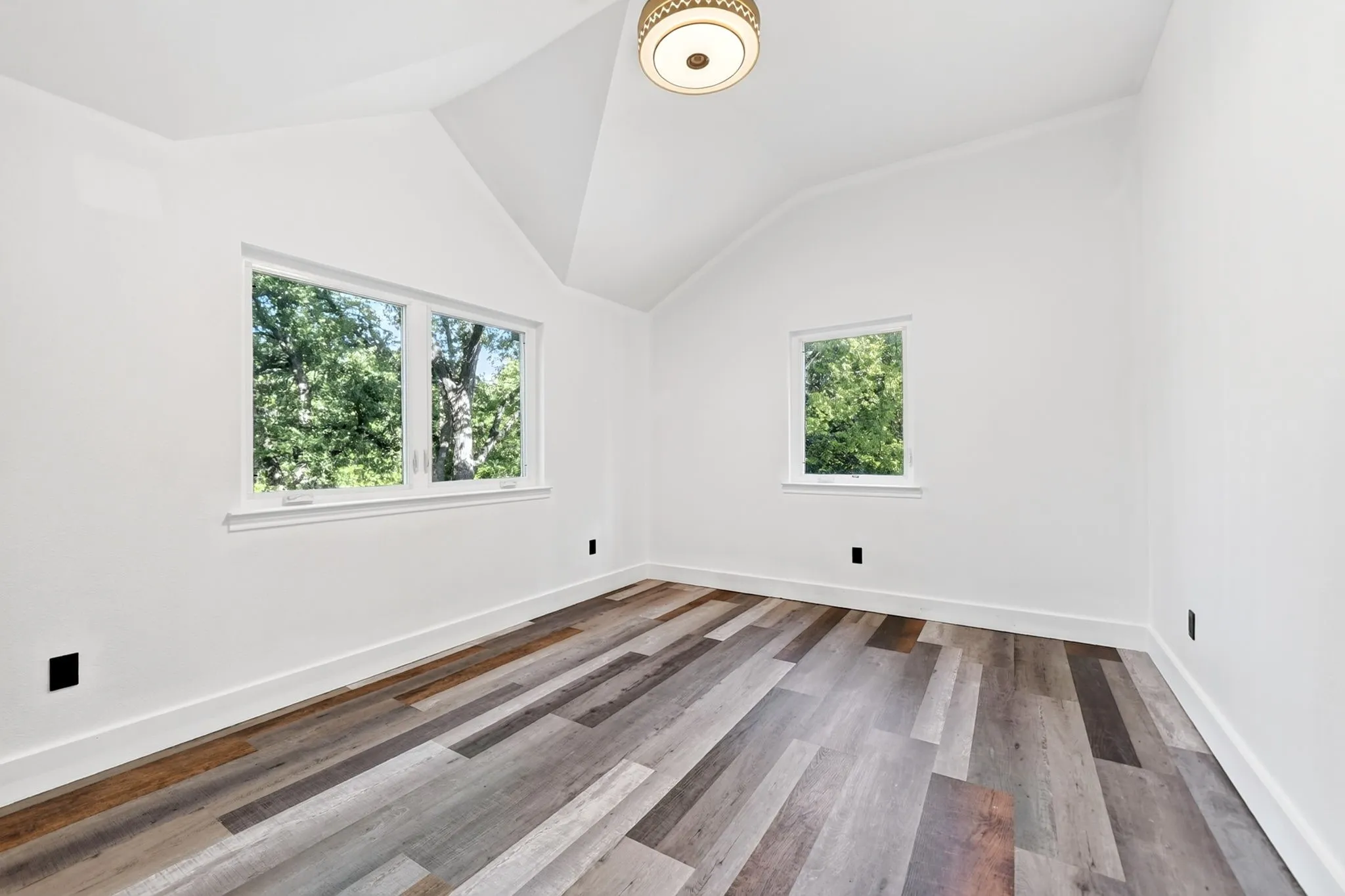 Vaulted ceiling, wood-finish flooring, recessed window, additional window, and a flush-mount ceiling light fixture