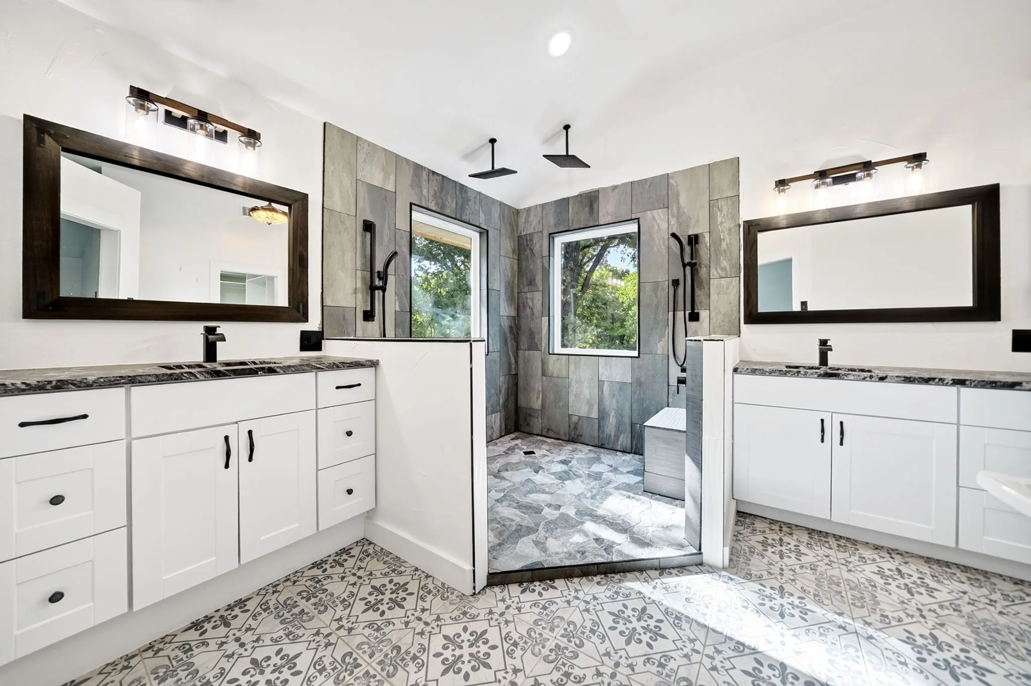 Dual vanity sinks with white cabinetry and dark countertops