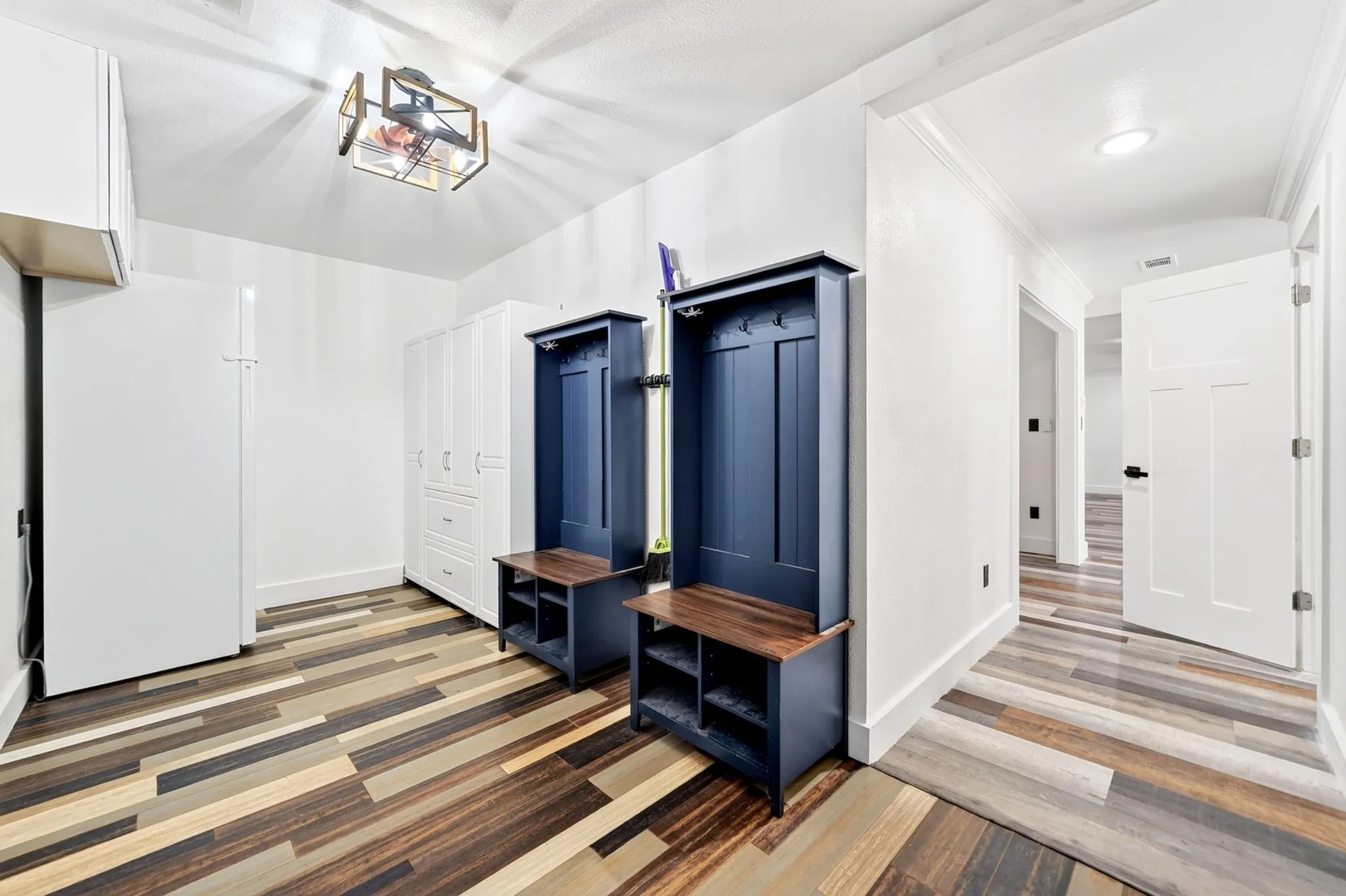 Wood-finish flooring, white built-in cabinetry, and modern ceiling light fixture