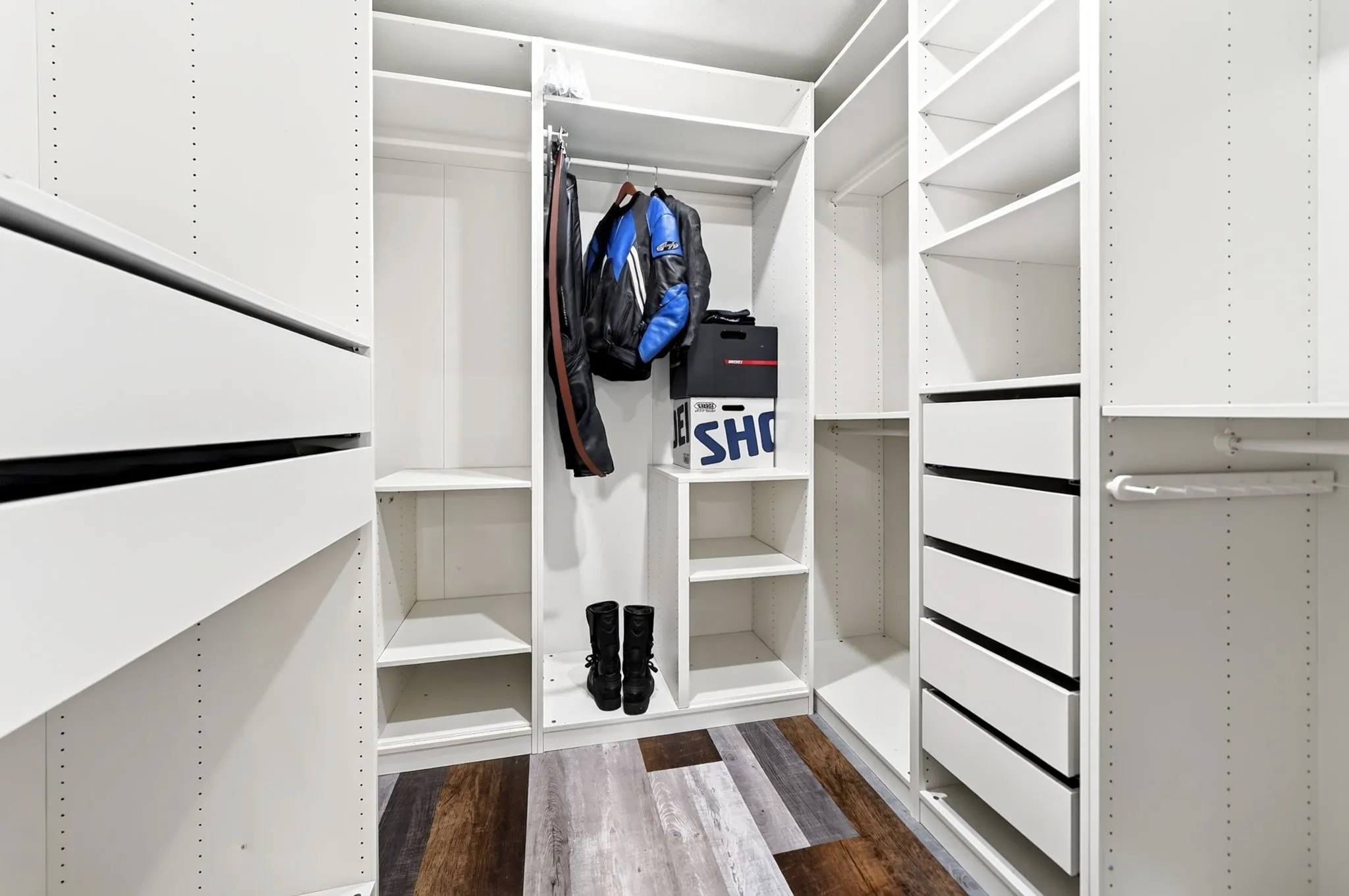 Custom closet organization system featuring multiple shelving units, integrated drawers, and hanging rods