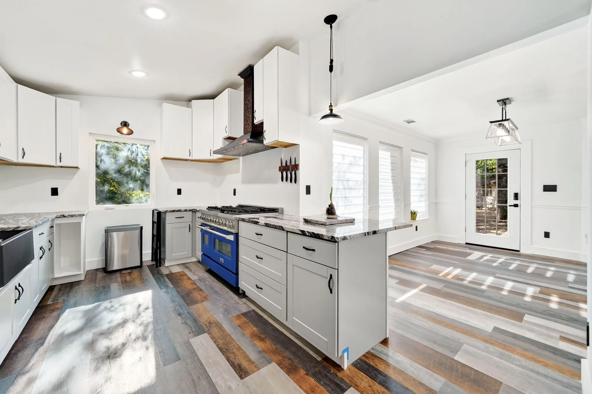 Kitchen featuring wood-finish flooring, white cabinetry, a blue range, gray countertops, and a full-light door
