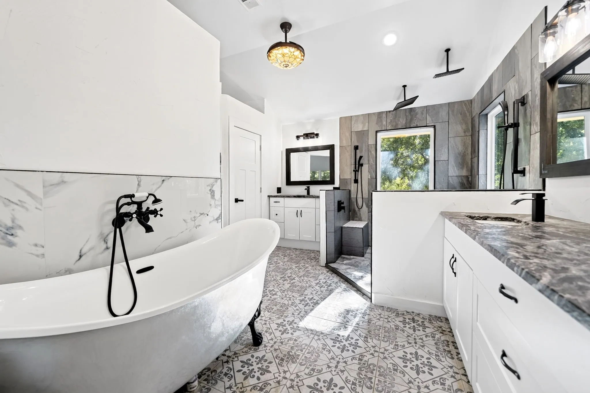 Clawfoot soaking tub, patterned floor tiles, dual vanity with undermount sinks, separate shower, and black fixtures