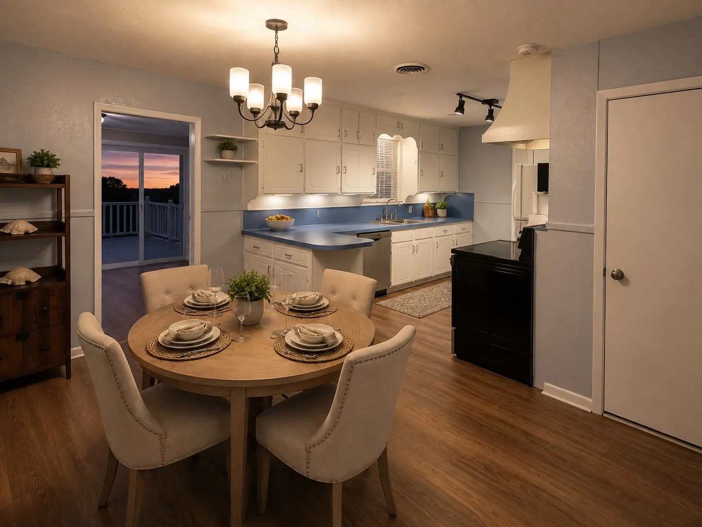 Kitchen dining area featuring white cabinetry, decorative lighting, and a sliding glass door to an outdoor deck.
Portions of this image have been digitally staged.