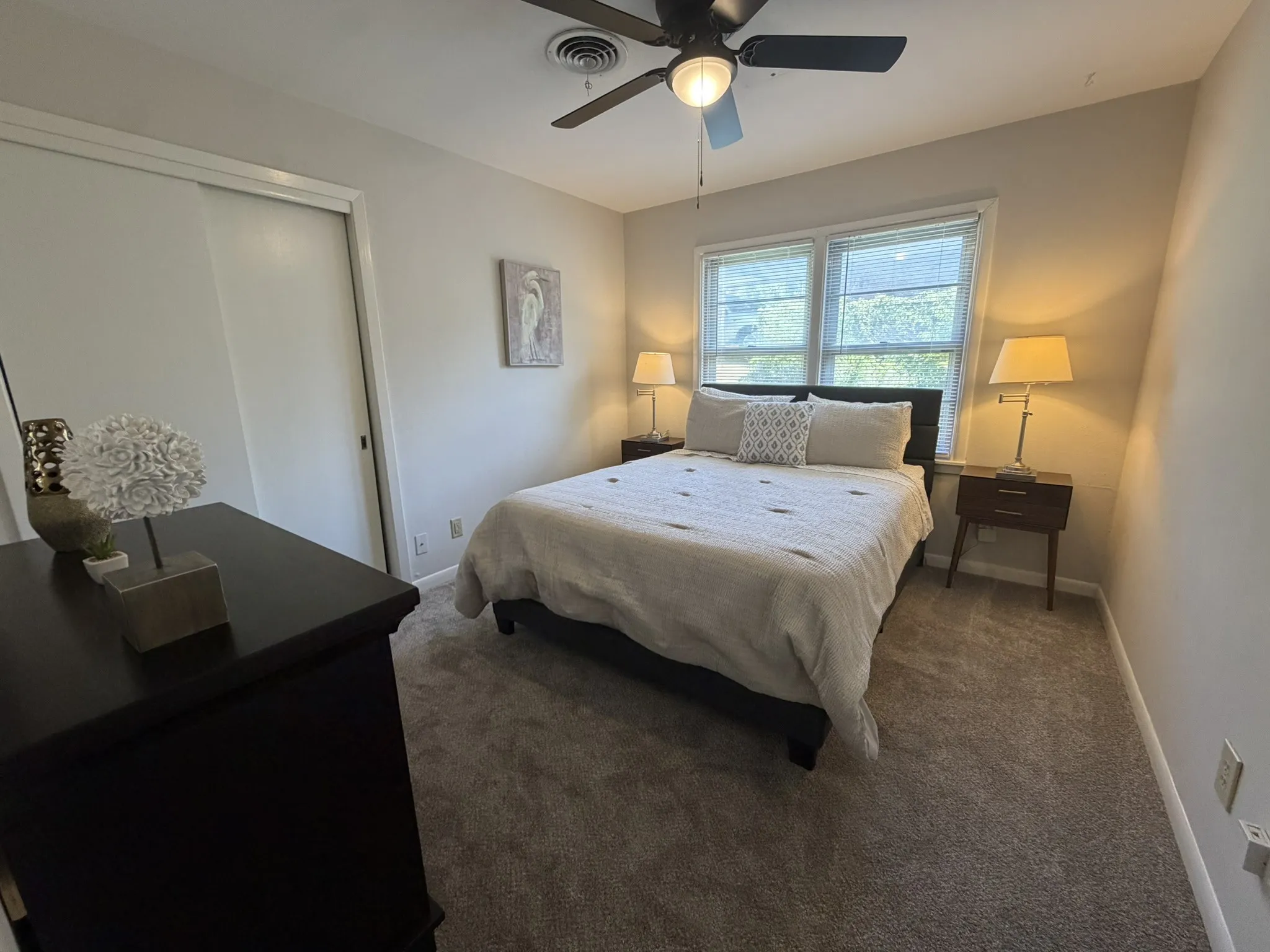 Soft gray carpeting with light neutral wall tones, dual windows, and ceiling fan