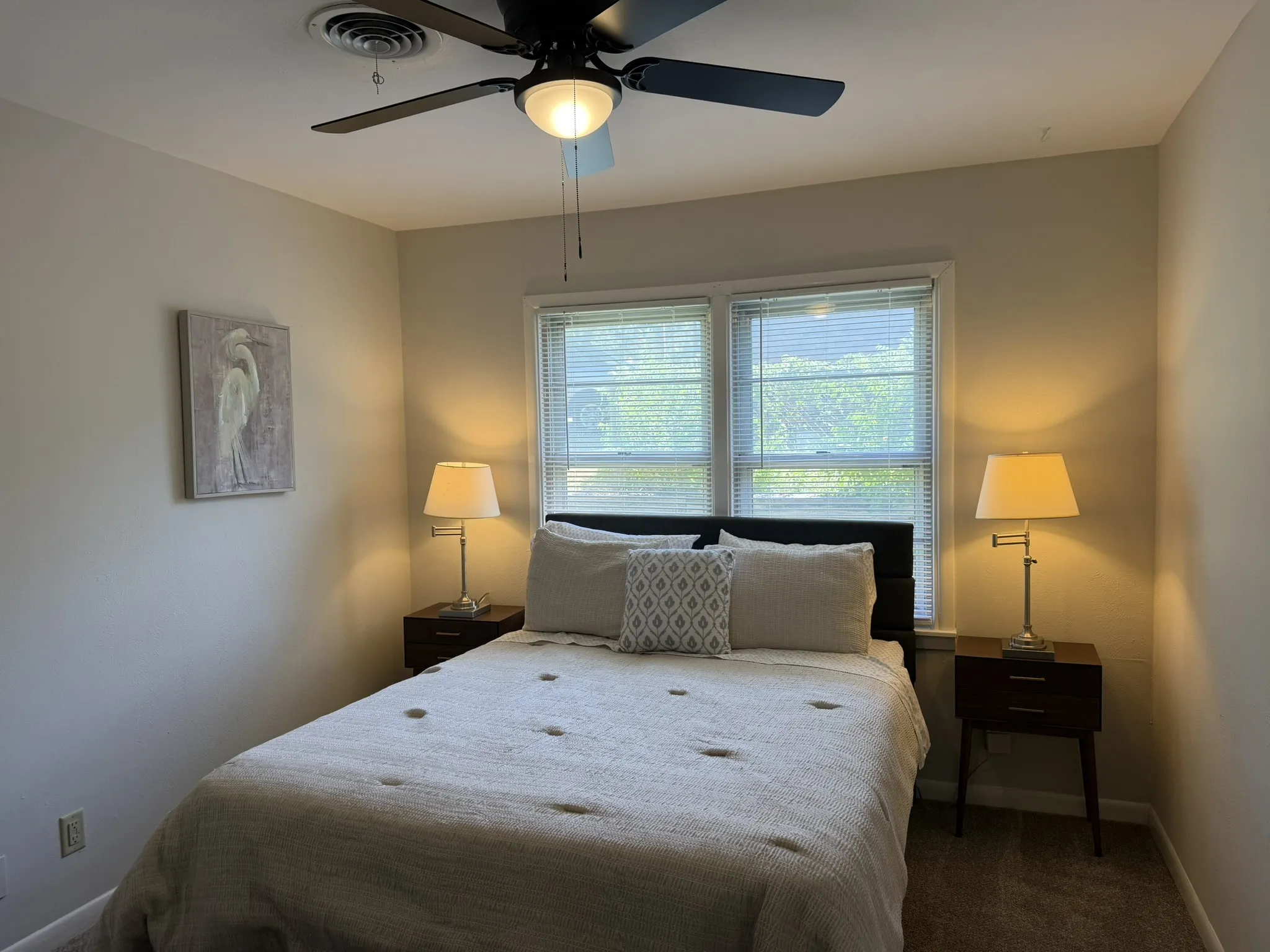Ceiling fan with integrated lighting, dual windows with blinds, and neutral wall tones