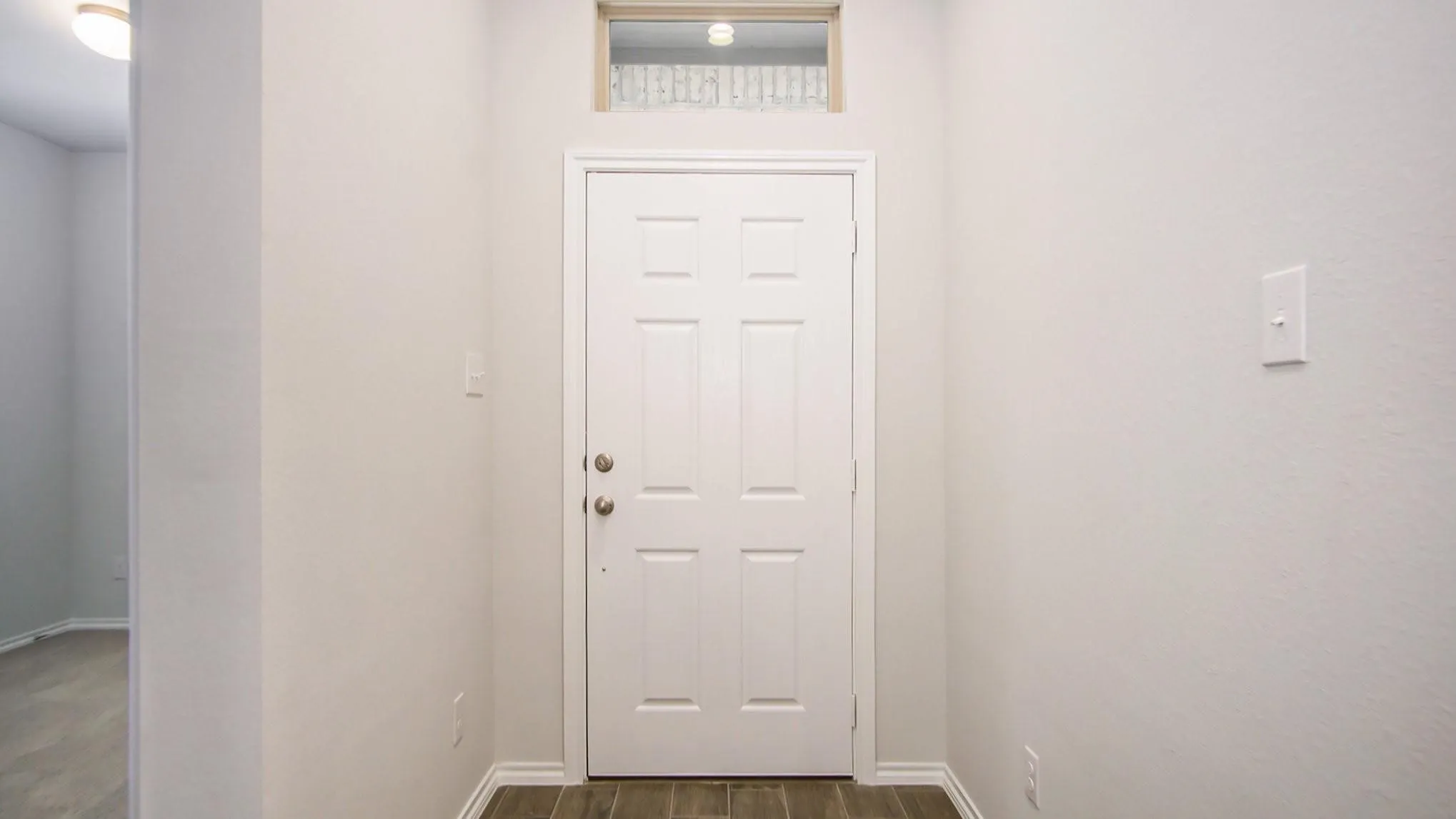 Entryway featuring a paneled door, transom window, and wood-finish flooring